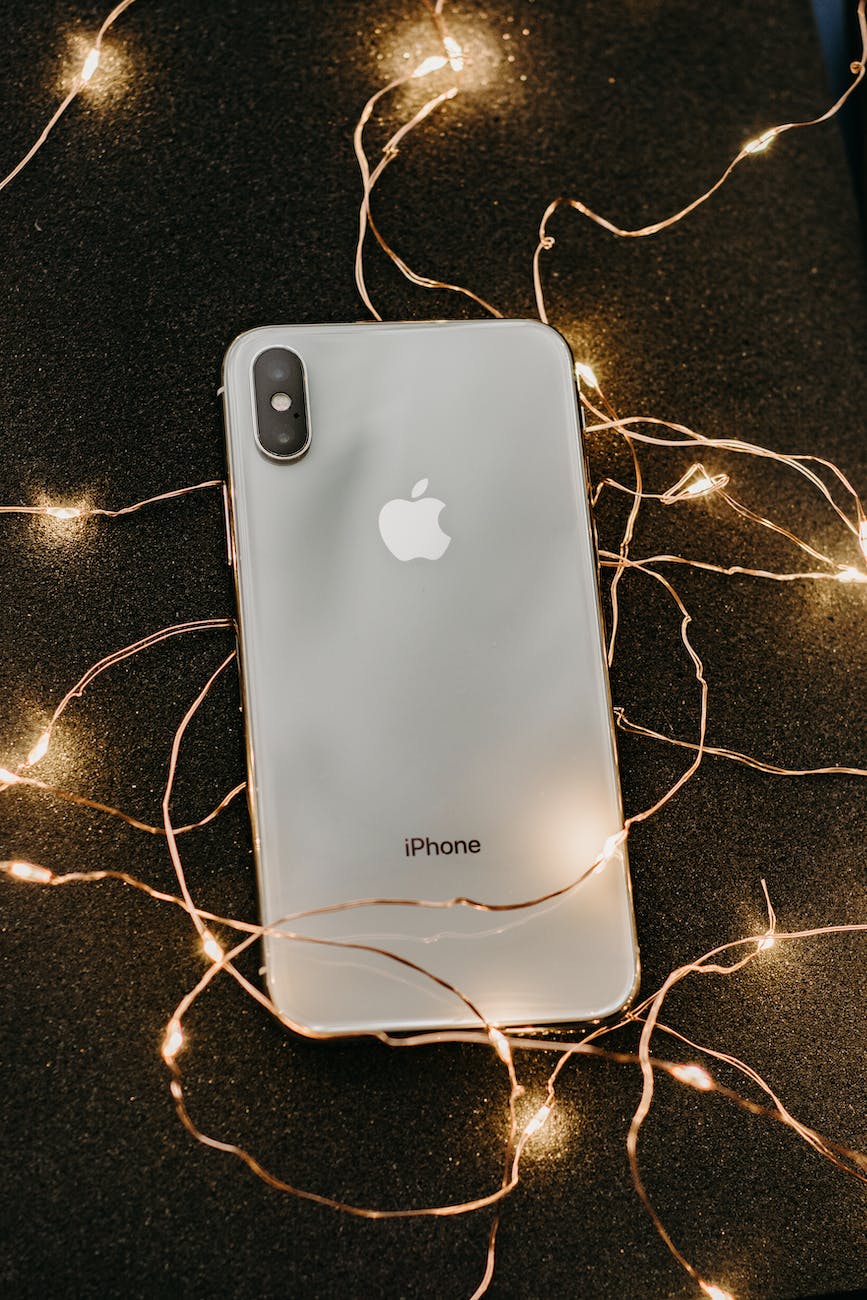 silver iphone x lying on pre lit string lights
