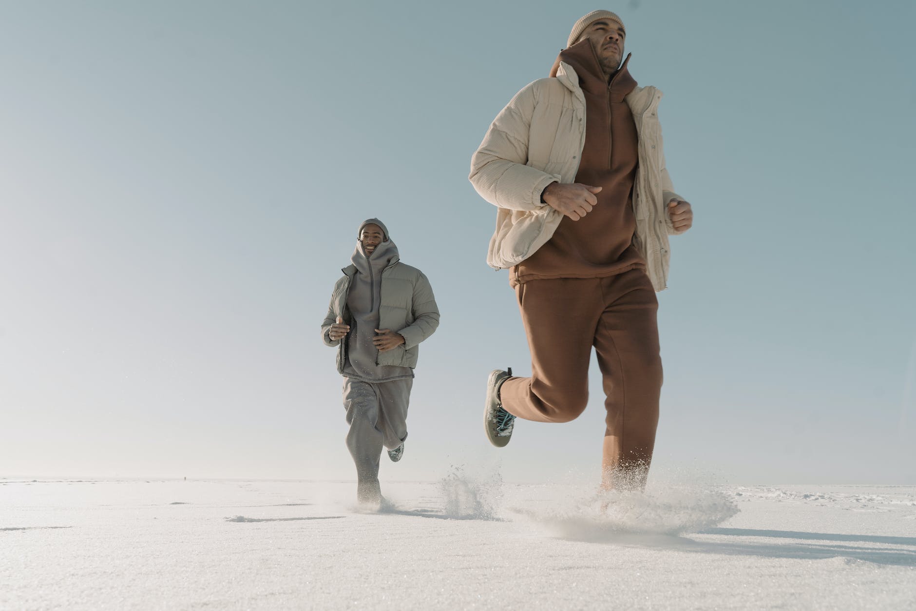 man wearing puffer jackets running on thick snow