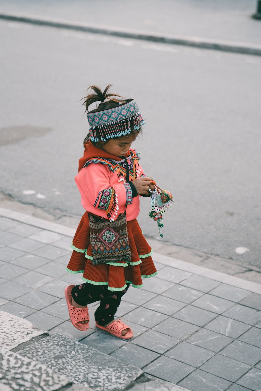 girl in traditional clothing walking on sidewalk