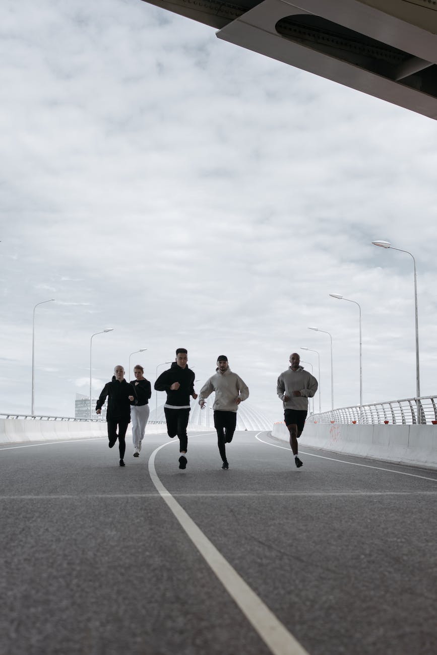 people running on the road under a cloudy sky