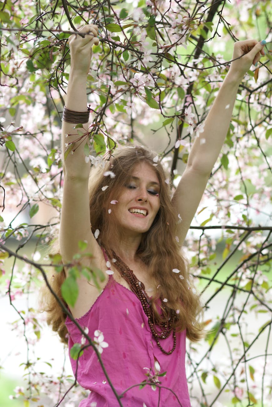 a woman in pink shirt is standing in a tree with blossoms