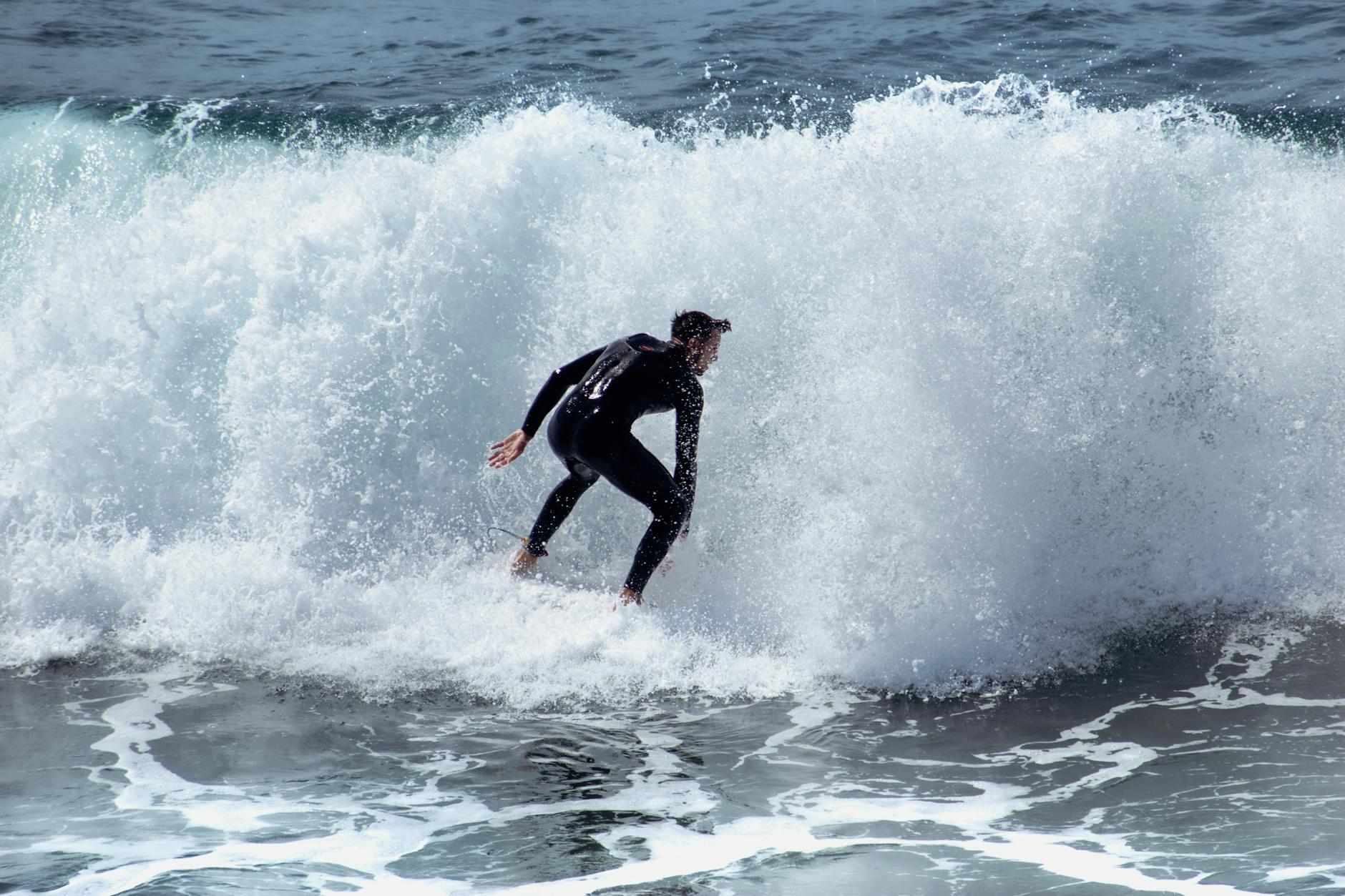 man in black rash guard surfing