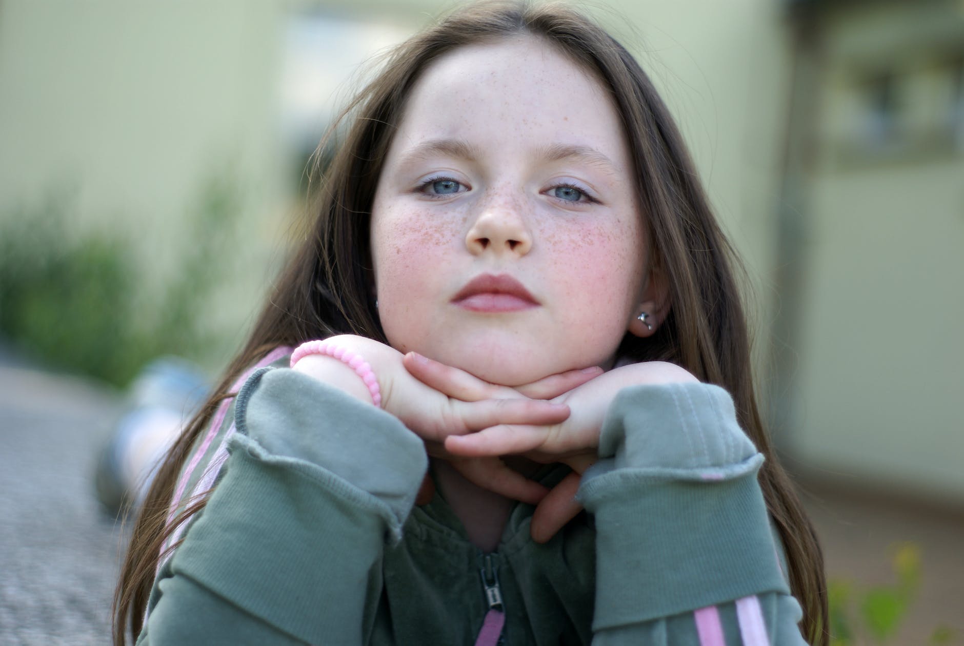 a young girl with freckles sitting on the ground