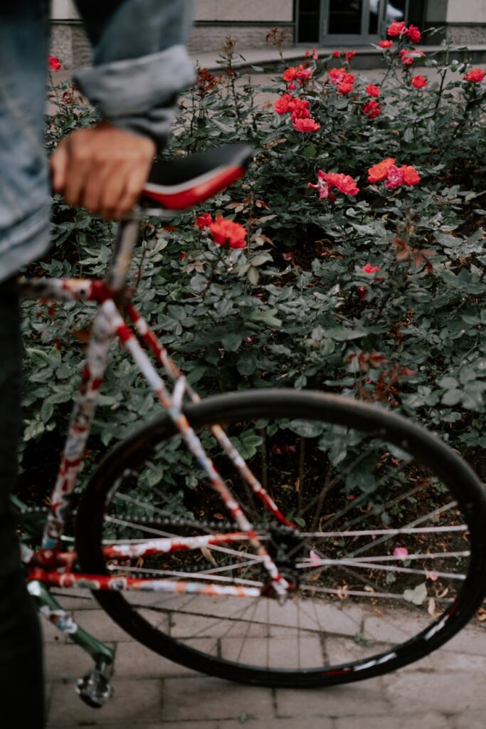 cyclist with a bicycle near a flower bed