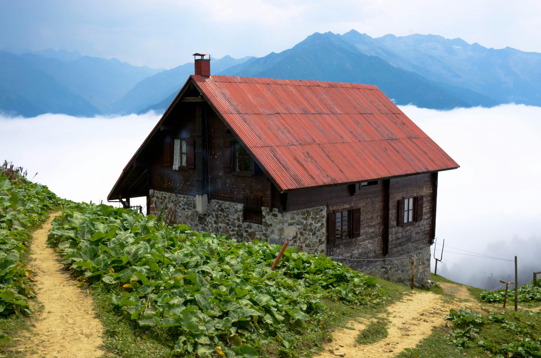 a hillside house above the clouds with view of mountains