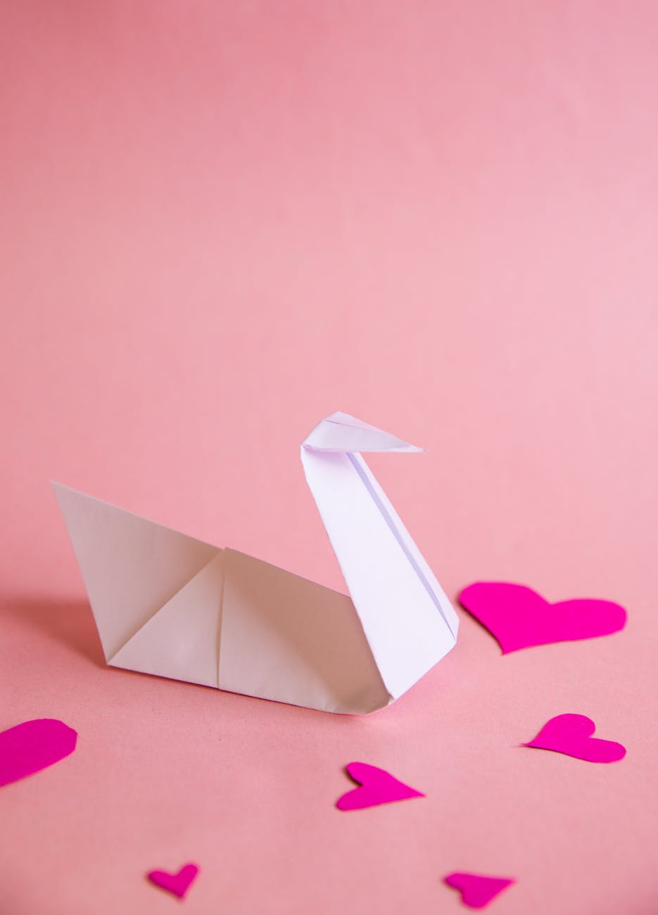 white paper boat on pink heart paper