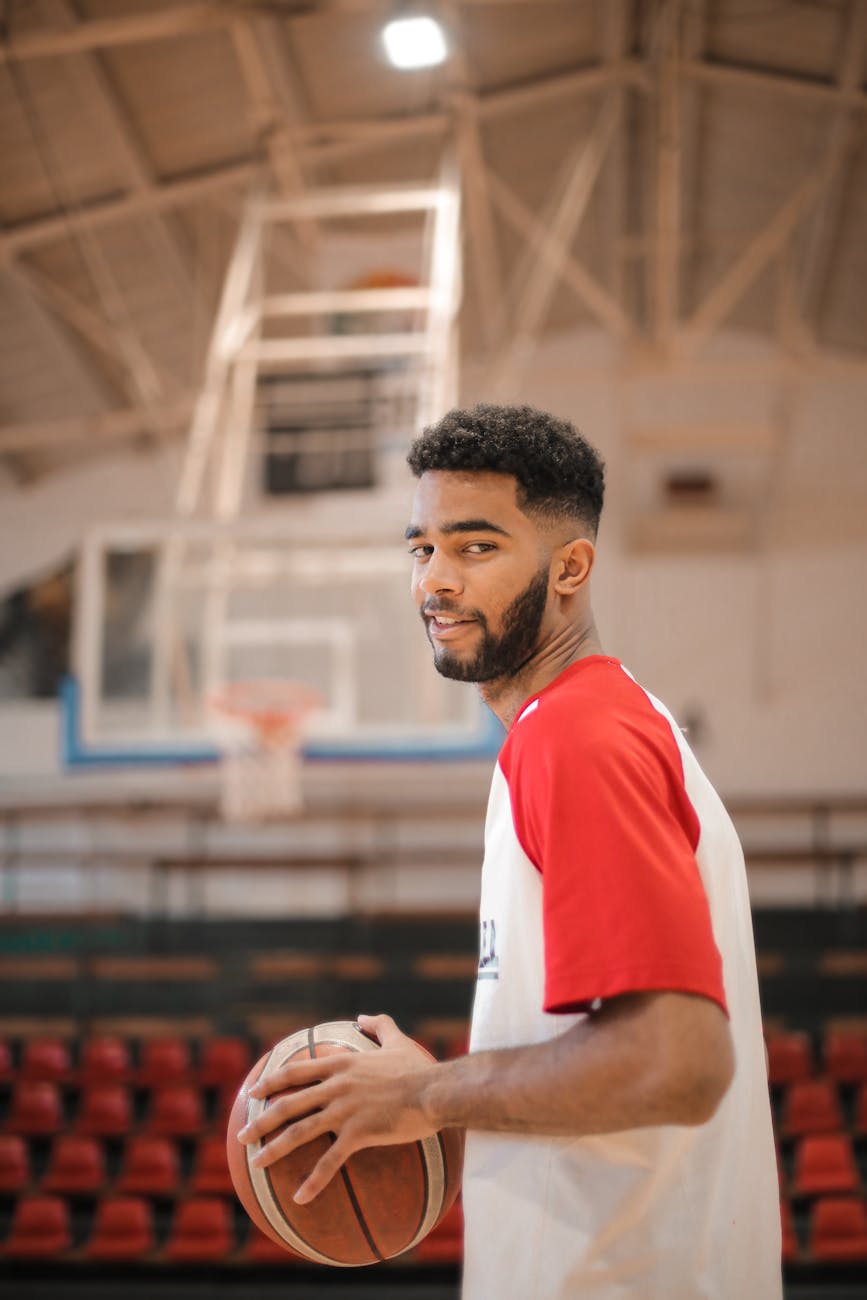 man in white and orange t shirt holding a basketball