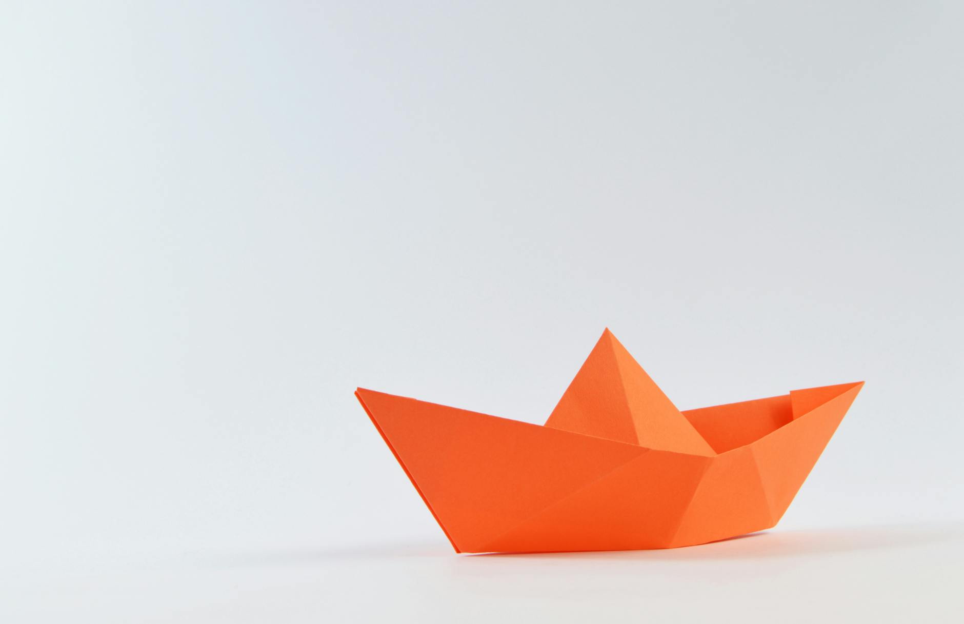 orange paper boat on white surface