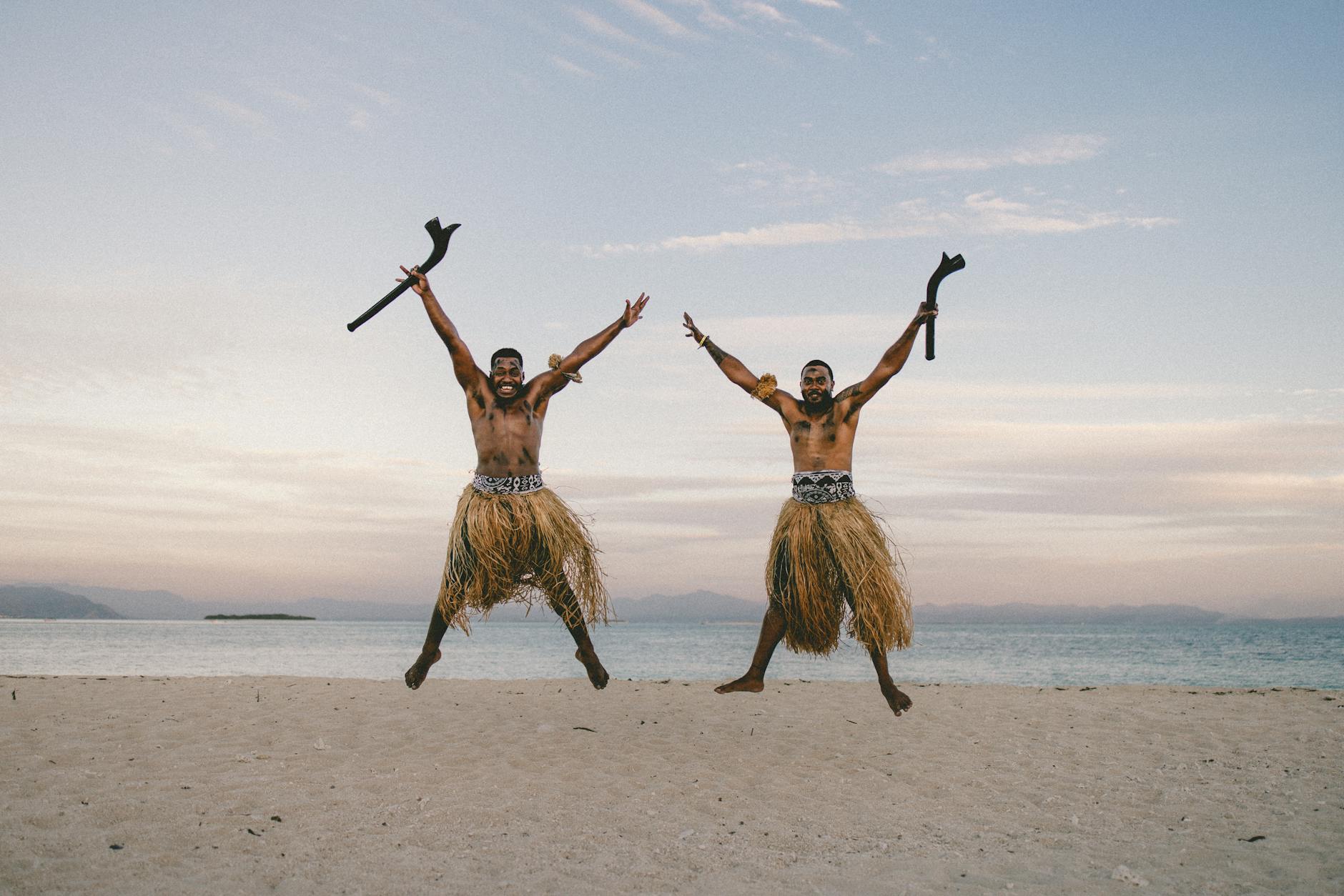 two men in skirts jumping against the landscape background