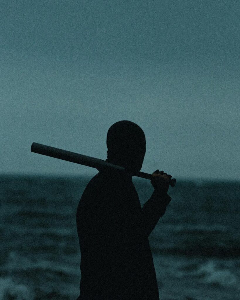 silhouette of man with baseball bat standing in sea shore