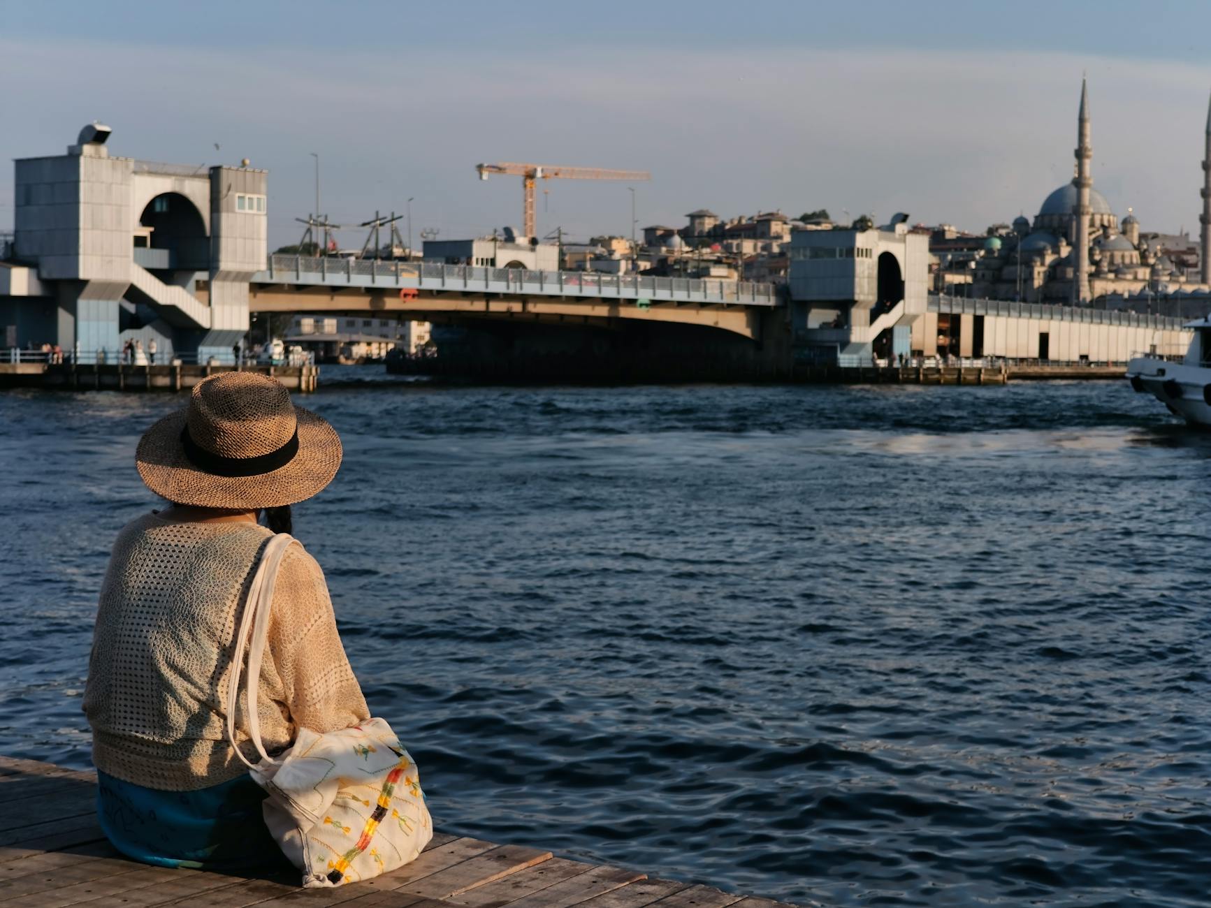 woman with hat sitting and looking at cityscape of istanbul turkey