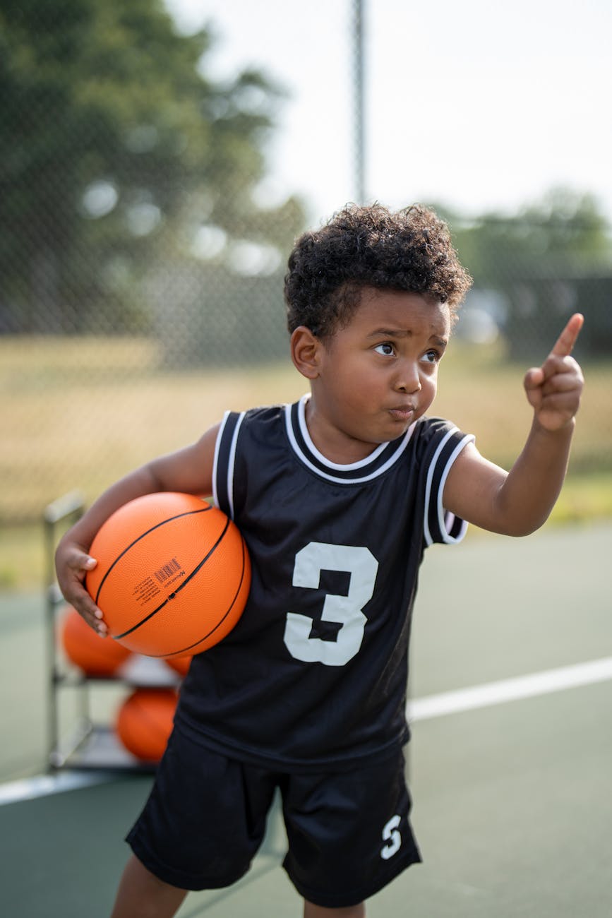 young child playing basketball on outdoor court