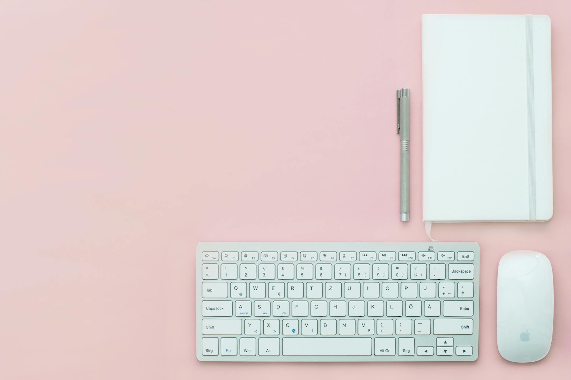 silver apple keyboard and magic mouse on a pink surface
