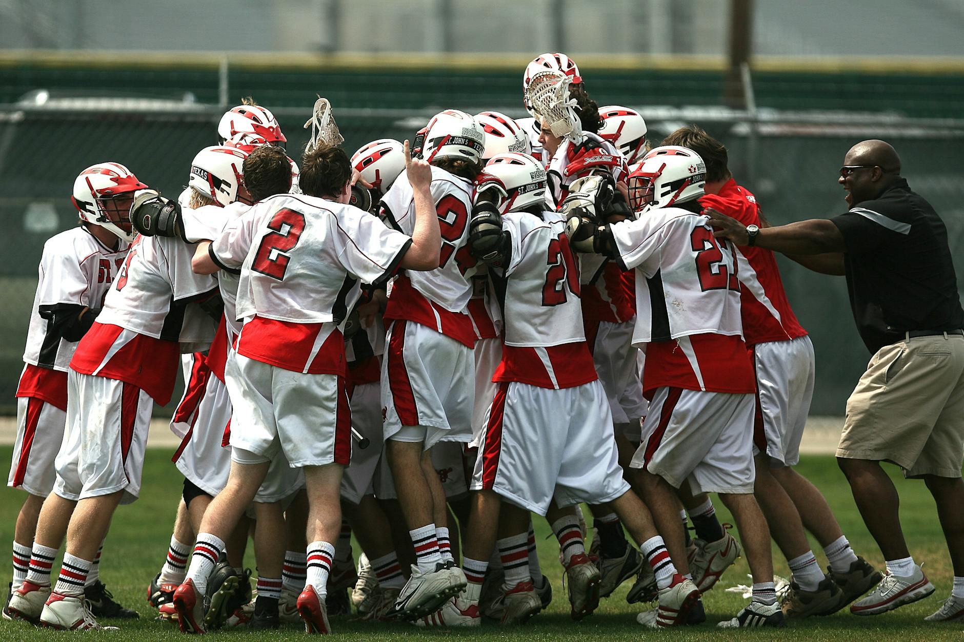 group of lacrosse players celebrating with coach during daytime