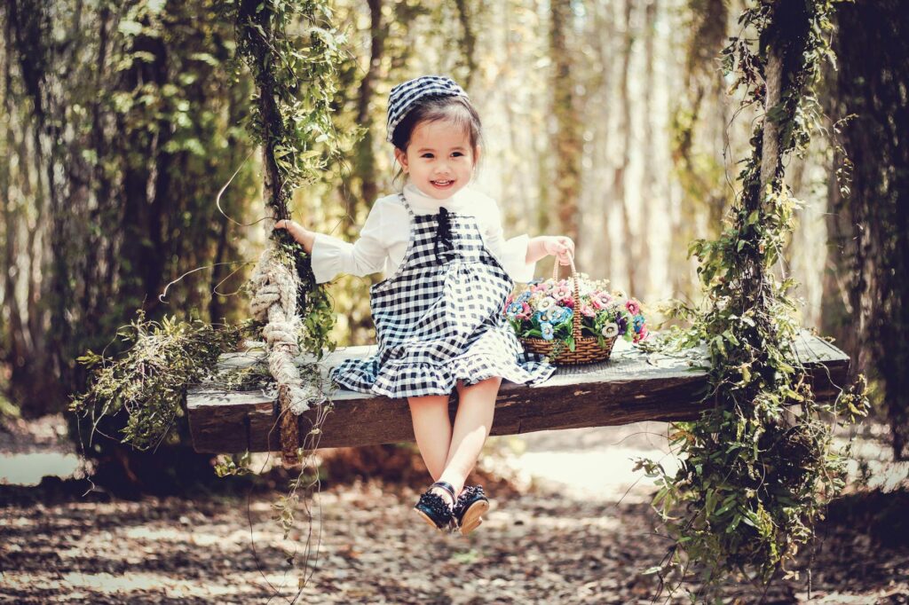 girl in black and white overall skirt holding basket with petaled flowers