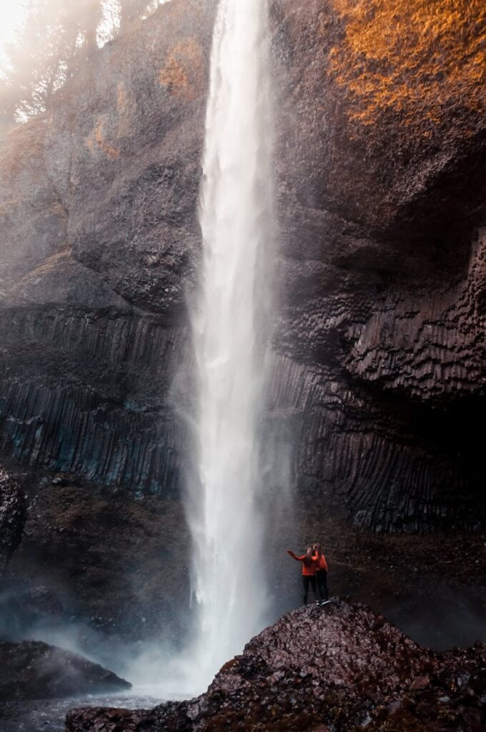 two man beside waterfall taken at daytime