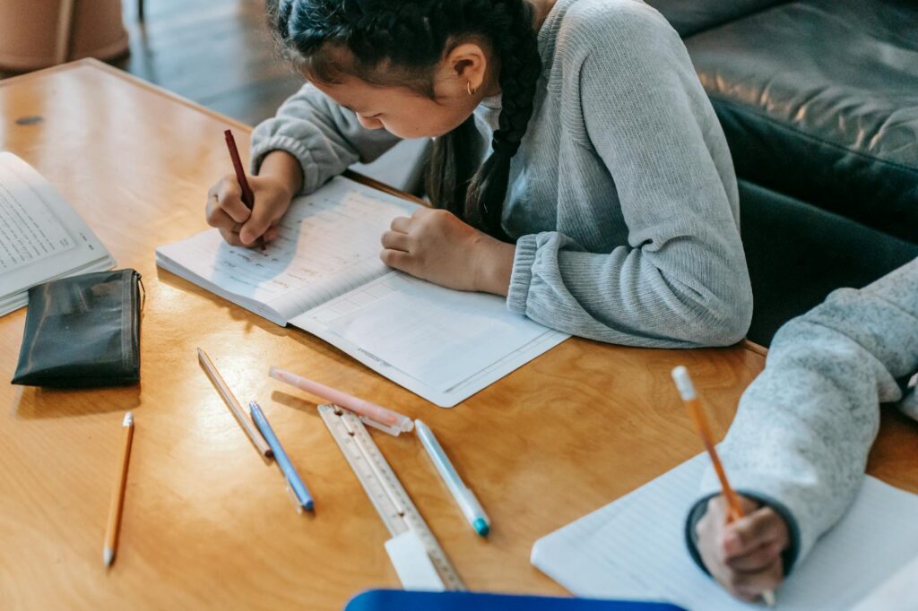 crop kids writing in copybooks