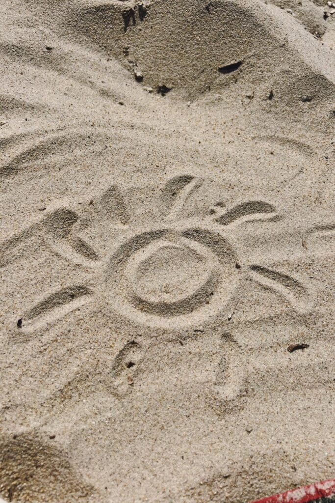 sun drawing etched in sandy beach
