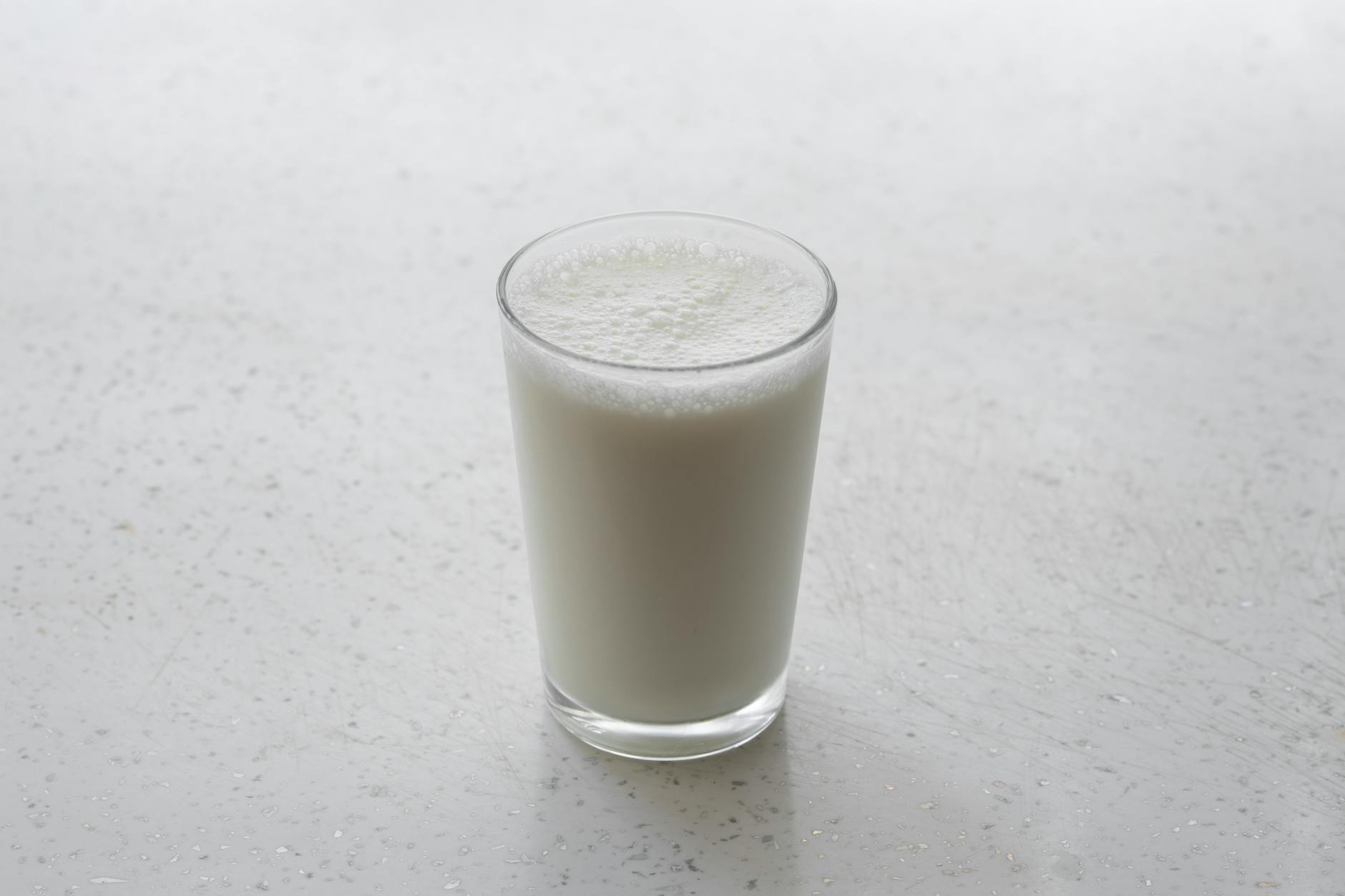 a glass of milk on a white surface