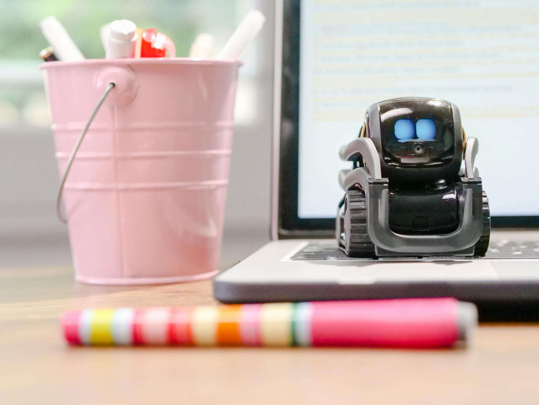 miniature toy robot on top of laptop s keyboard