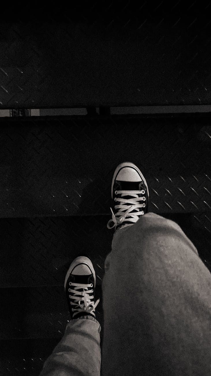 black and white photo of legs in trainers