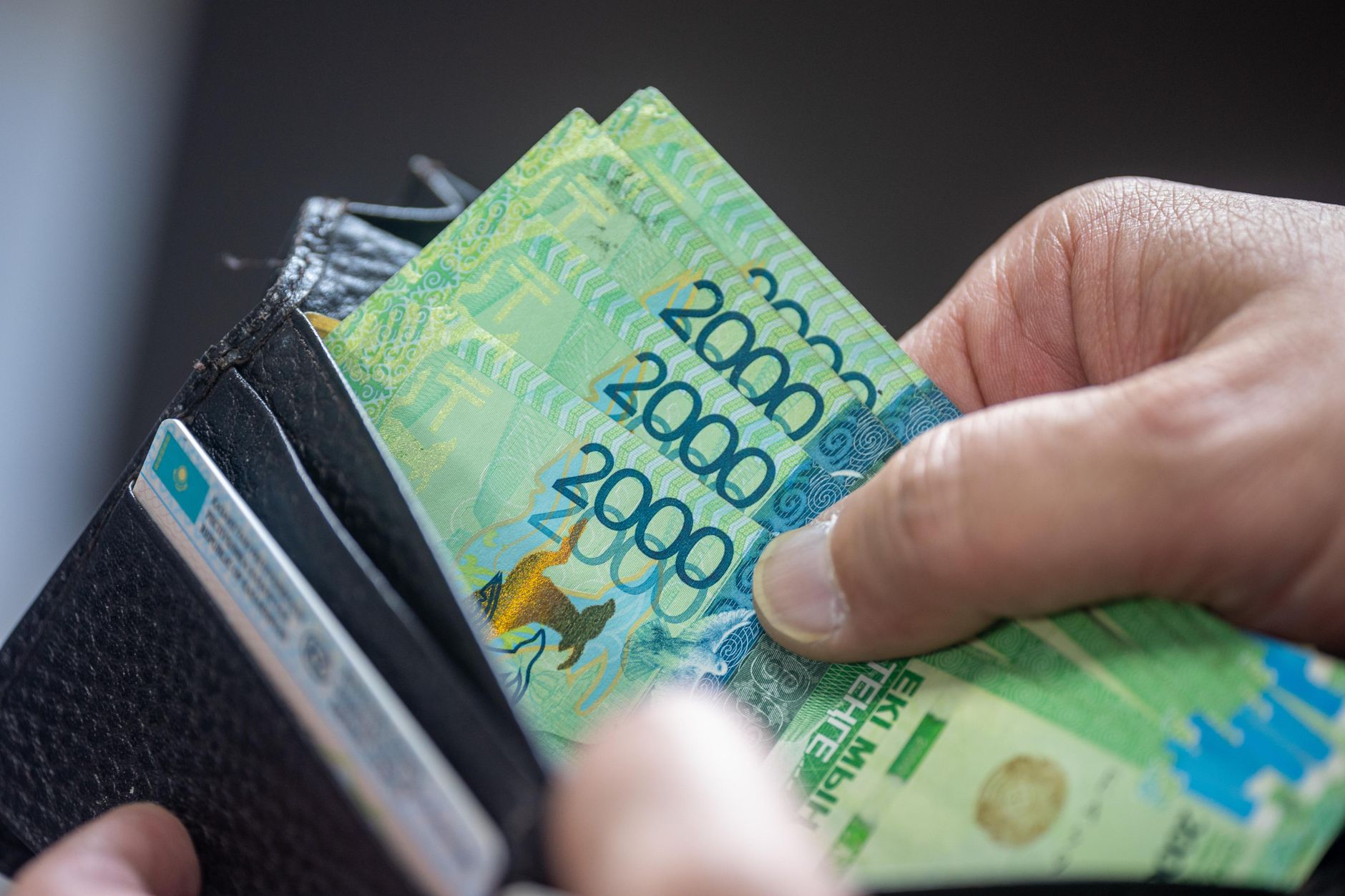 hand holding kazakhstan tenge in wallet
