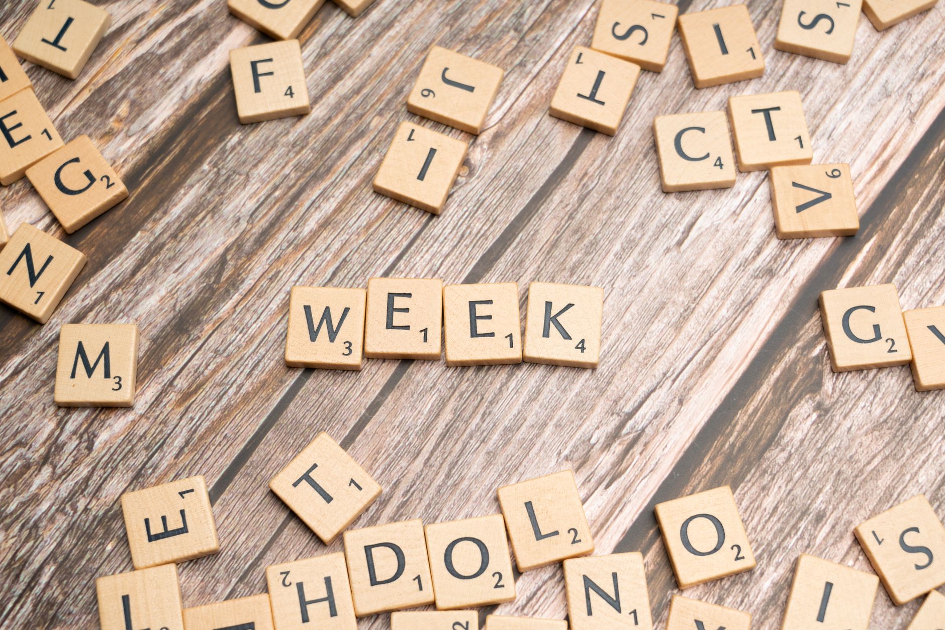 scrabble letters spelling the word week on a wooden table